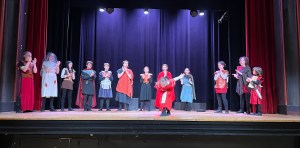 The YSP East ensemble are taking their bows after a performance of Julius Caesar. One young actor is taking their bow, the others are clapping.